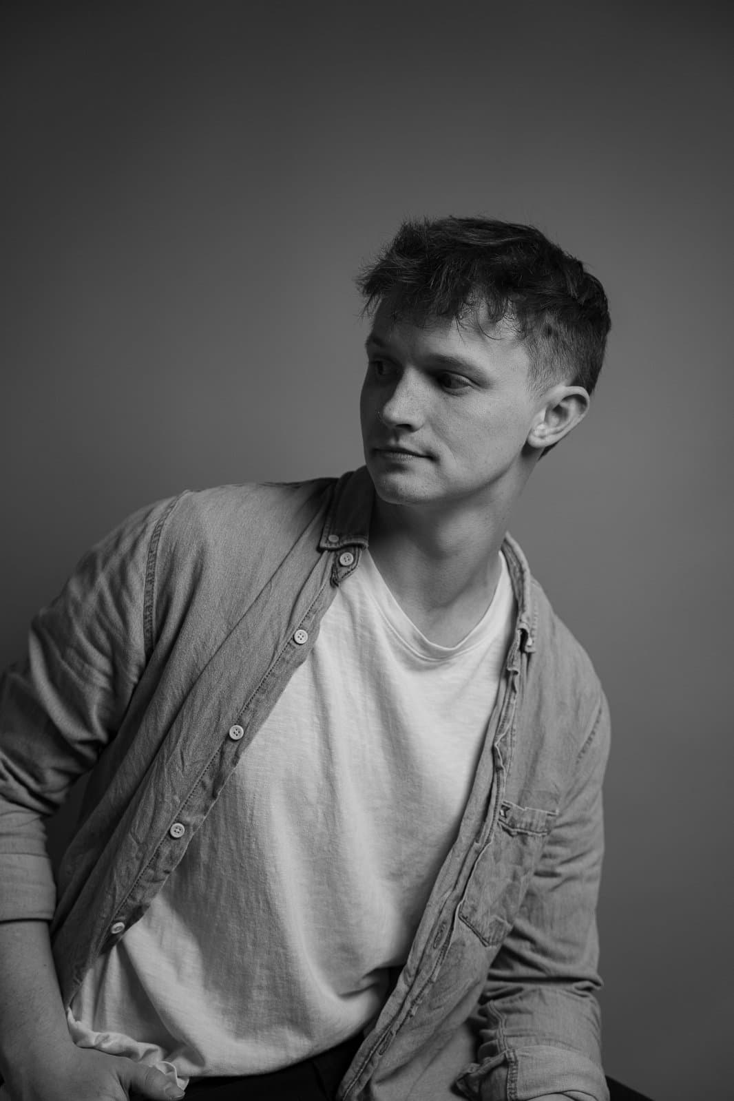 Ryker Marble, in a denim shirt over a white tee, looking off to the side. Black and white.