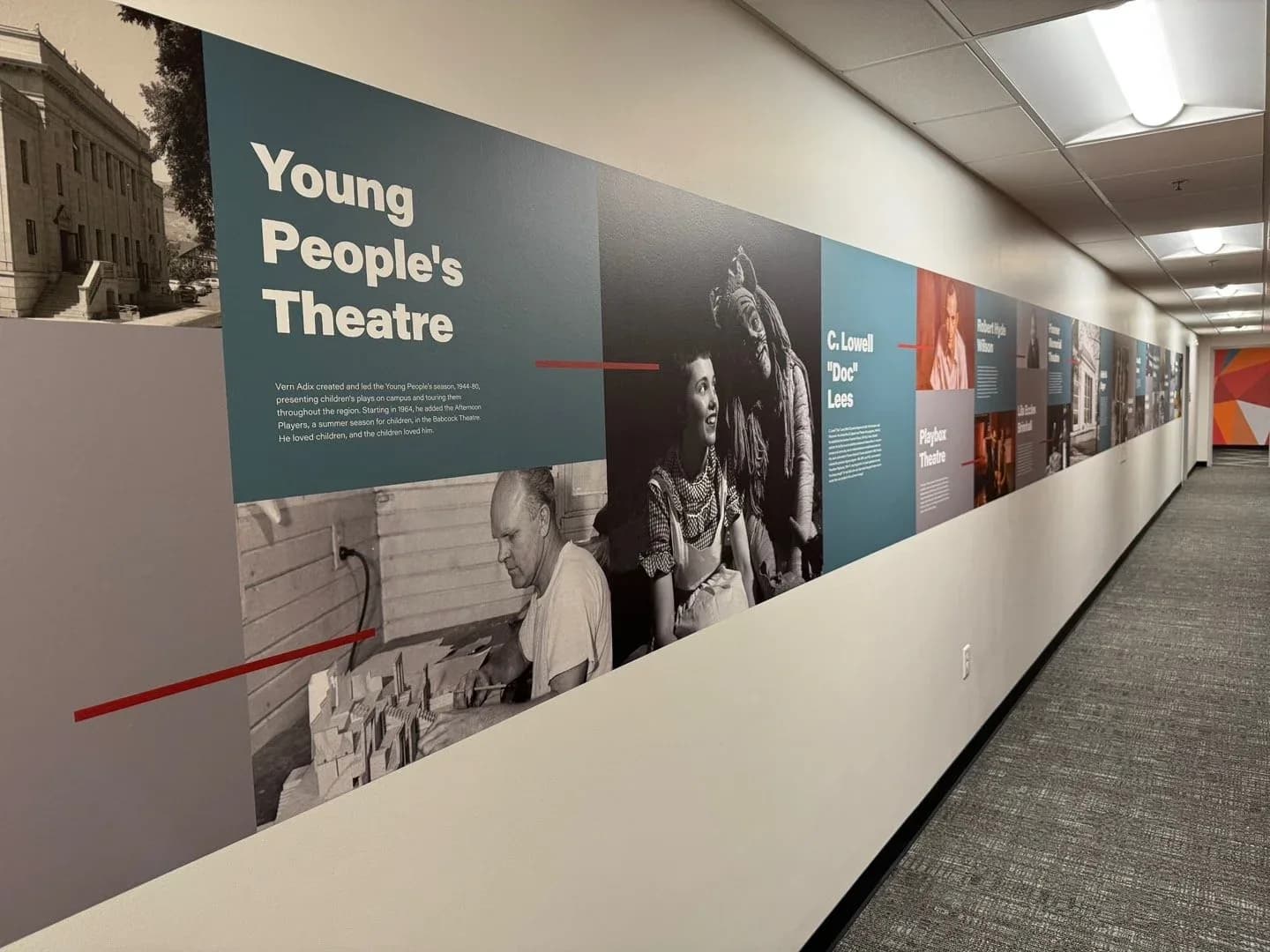 The installed timeline up close: a teal Young People’s Theatre panel with black-and-white photos of a man building a set model and a young actor beside a costumed figure.